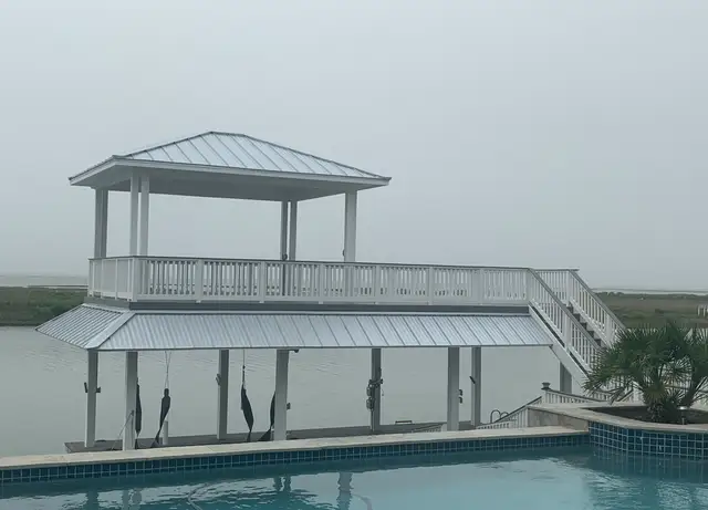 Two-story boathouse with metal roof and upper deck on the water in Galveston